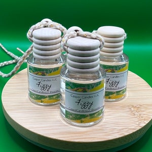 May include: Three clear glass bottles with wooden stoppers and string hangers. Each bottle has a label that reads "Casper Candles LLC Fizzy CasperCandlesLLC Etsy.com".