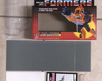 May include: A vintage Transformers toy box with a red, white, and blue background. The box features a yellow and black robot toy with the text "The Transformers" and "More Than Meets The Eye".