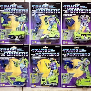 May include: A set of 10 Transformers action figures from the 1980s. The figures are all in their original packaging and are in good condition. The figures are all from the Construction line and include Long Haul, Scrapper, Hook, Mixmaster, and Excavator. The packaging is purple and green with the Transformers logo and the figure's name.