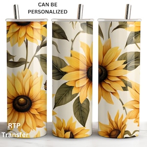 May include: A set of three stainless steel tumblers with a sunflower pattern. The tumblers are cream colored with yellow sunflowers and green leaves. The text "CAN BE PERSONALIZED" is at the top of the image. The text "RTP Transfer" is at the bottom of the image.