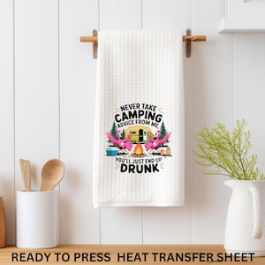May include: White waffle-weave kitchen towel with a camping-themed graphic. The graphic features a yellow camper, pink flamingos, and the text "NEVER TAKE CAMPING ADVICE FROM ME. YOU'LL JUST END UP DRUNK."