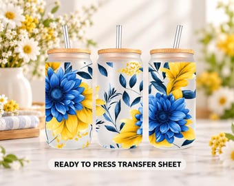 May include: Three frosted glass tumblers with bamboo lids and metal straws, featuring a vibrant floral pattern of large blue and yellow flowers with dark blue leaves. The text READY TO PRESS TRANSFER SHEET is printed at the bottom of the image.