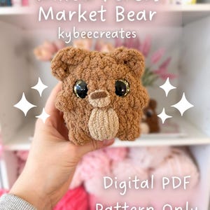 Puede incluir: Un oso de ganchillo con pelaje marrón, ojos negros grandes con purpurina dorada y un hocico beige. El texto "Willow Forest Market Bear" y "kybeecreates" son visibles. También se muestran las palabras "Digital PDF Pattern Only".