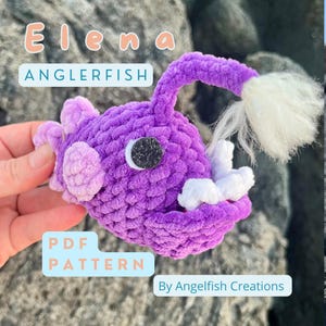 May include: Purple crocheted anglerfish plush toy with a white lure and a white fluffy tail. The toy is labeled "Elena Anglerfish PDF Pattern by AngelFish Creations".
