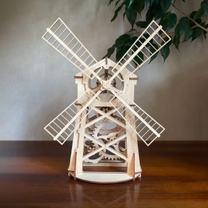 May include: A wooden model of a windmill with intricate gears and blades. The windmill is made of light wood and has a natural finish.