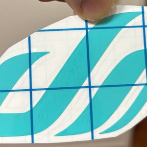 May include: A teal blue vinyl decal with a stylized wave design. The decal is on a white background with a blue grid.