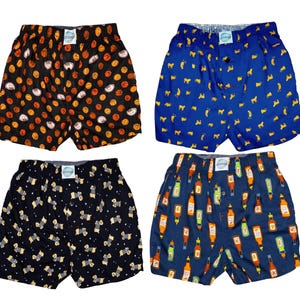 May include: Four pairs of boxer shorts with various patterns. One pair is black with basketballs, another is blue with yellow dog silhouettes, a third is black with zebra-like patterns, and the last is blue with condiment bottles.