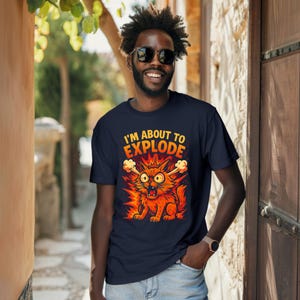 May include: Navy blue t-shirt featuring a cartoon cat with the text "I'M ABOUT TO EXPLODE". The cat is depicted in shades of orange and red, with steam coming from its ears, set against a fiery background.