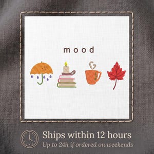 May include: A white square fabric patch featuring the word mood in brown lowercase letters above four icons: an orange umbrella with purple raindrops, a lit candle on a stack of books, an orange mug with steam, and a red maple leaf.