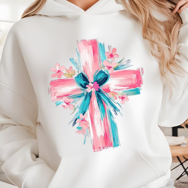 Puede incluir: Sudadera blanca con un dise&ntilde;o de cruz rosa y azul con flores y un lazo. La cruz est&aacute; pintada en un estilo de pinceladas.