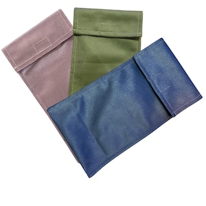 May include: Three rectangular pouches in shades of mauve, olive green, and blue. Each pouch has a flap closure with a stitched rectangular detail. The pouches are made of a textured fabric and are arranged diagonally.