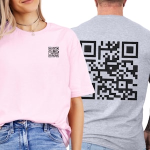 May include: Two short-sleeved t-shirts, one light pink and one gray. The pink shirt has a small black QR code on the chest. The gray shirt has a large black QR code on the back. Both shirts are plain.