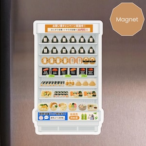 May include: A refrigerator-shaped magnet featuring various Japanese food items. The magnet includes images of onigiri, sushi, and other prepared foods. Text in Japanese is visible at the top and bottom of the magnet.