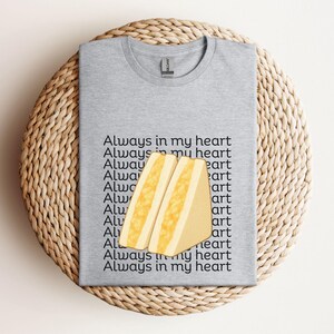 Sport grey t-shirt featuring Japanese egg sandwich (tamago sando) graphic with Japanese text, folded flat on woven mat