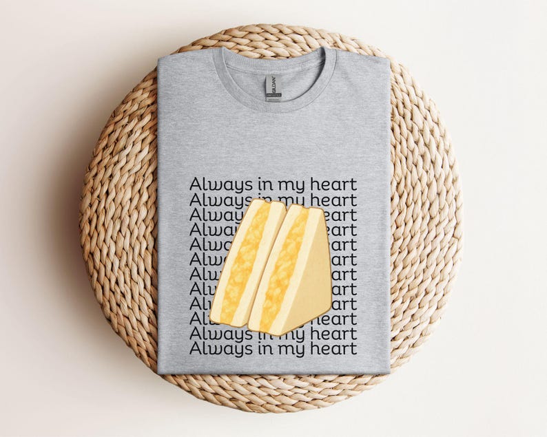 Sport grey t-shirt featuring Japanese egg sandwich (tamago sando) graphic with Japanese text, folded flat on woven mat