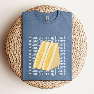 Heather indigo t-shirt with large tamago sando graphic and Japanese text, flat laid on woven round placemat