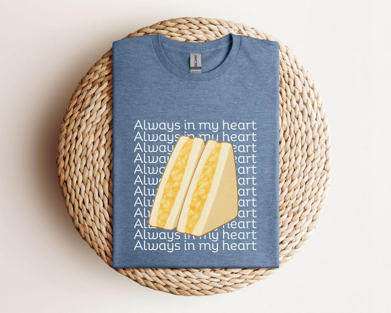 Heather indigo t-shirt with large tamago sando graphic and Japanese text, flat laid on woven round placemat