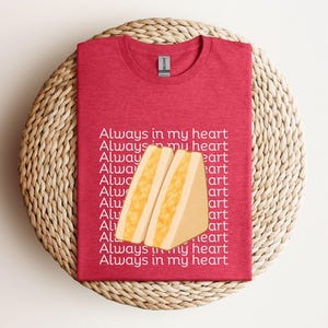 Heather red t-shirt with yellow Japanese egg sandwich design and bold Japanese text, styled on rustic wicker surface