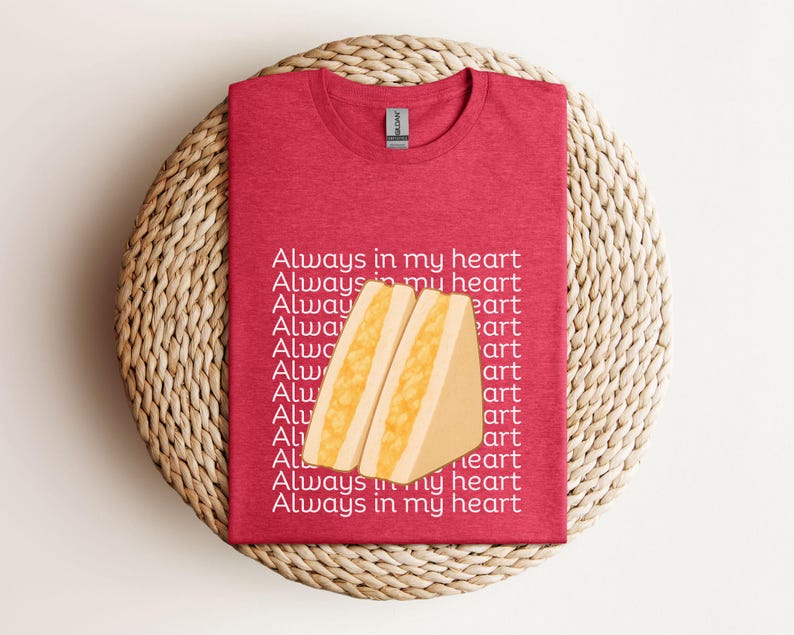 Heather red t-shirt with yellow Japanese egg sandwich design and bold Japanese text, styled on rustic wicker surface