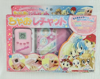 May include: A pink and white box with the text "Cha-o Le Chat" on the front. The box contains a pink handheld electronic game with a screen and buttons. The box also features illustrations of anime characters.
