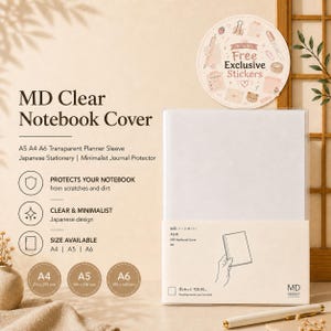 May include: A clear MD notebook cover in A5 size, presented in its original packaging. The packaging features text including 'MD Clear Notebook Cover', 'A5 A4 A6', and 'Includes Free Exclusive Stickers'. A white pen rests on the surface below.