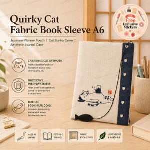 May include: An A6 fabric book sleeve featuring a cream-colored front panel with a black line drawing of a cat lying down with a small kettle on its stomach. A dark blue vertical strip runs along the right side, and a black cord with a fish charm is attached.