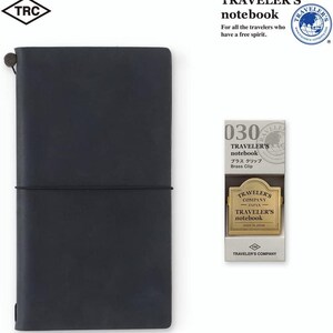 May include: A dark blue Traveler's notebook with a matching elastic closure, and a brass clip. The notebook is accompanied by a brass clip in a white box. The text on the box reads "Traveler's notebook" and "Brass Clip".