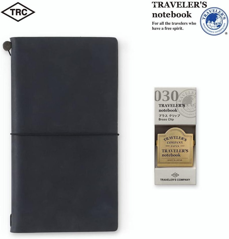 May include: A dark blue Traveler's notebook with a matching elastic closure, and a brass clip. The notebook is accompanied by a brass clip in a white box. The text on the box reads "Traveler's notebook" and "Brass Clip".