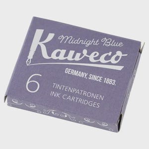 Puede incluir: Una caja de cartuchos de tinta Kaweco Midnight Blue. La caja es de color morado apagado con texto blanco que dice "Kaweco", "Midnight Blue", "Germany, Since 1883" y "6 Ink Cartridges". La caja tiene remolinos decorativos.