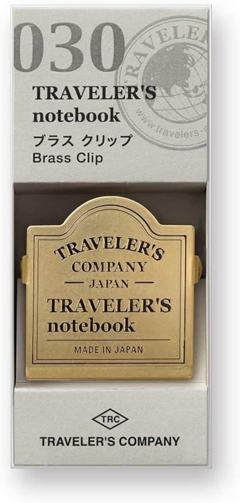 May include: A brass clip for a Traveler's notebook, presented in a box. The clip features the text "TRAVELER'S COMPANY JAPAN" and "TRAVELER'S notebook". The box has the number "030" and the words "TRAVELER'S notebook" and "Brass Clip".