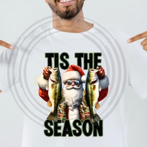 May include: A white t-shirt with a Christmas-themed design featuring Santa Claus holding two fish and the text "Tis the Season".