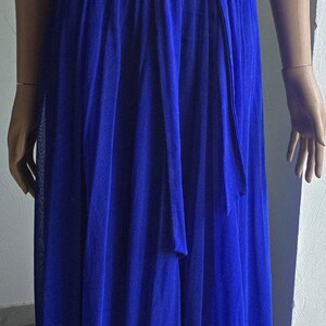 May include: A floor-length royal blue sleeveless dress featuring a round neckline, gathered fabric detailing at the shoulders, and a matching fabric tie belt at the waist. The garment is constructed from a lightweight, semi-sheer pleated material.