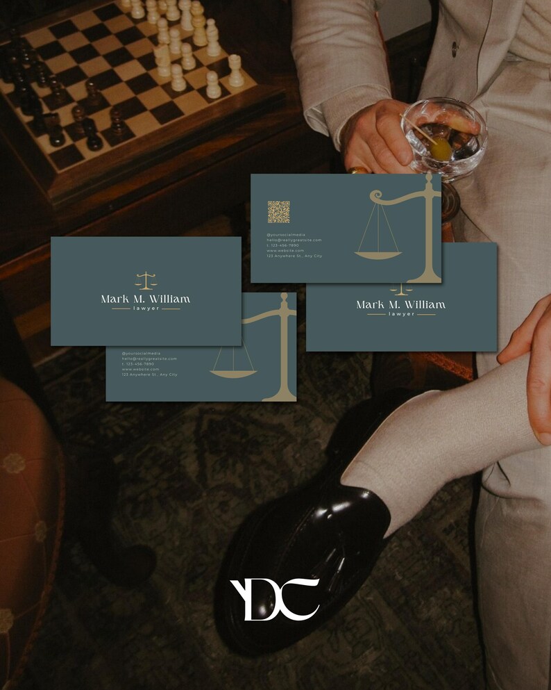 May include: Business cards with a teal background and gold scale of justice graphic. The cards display the name "Mark M. William - lawyer" in white text. A chess board with pieces is visible in the background.