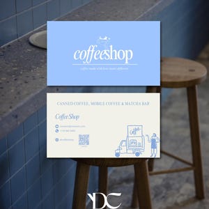 May include: Two rectangular business cards. The top card is light blue with the white text "coffeeshop" and "coffee made with love tastes different". The bottom card is off-white with blue text, a QR code, and a line drawing of a coffee cart.