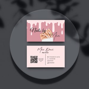 May include: Pink business card with the text "Nails by Mia" and a hand with manicured nails. The bottom of the card has the text "Mia Dewi Nail Artist" with contact information and a QR code.