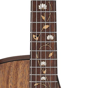 Op de afbeelding: Close-up van een gitaarhals met een donkerbruine toets. De toets heeft ingelegde lotusbloem- en bladmotieven van parelmoer. De body van de gitaar is zichtbaar en toont een natuurlijke houtnerf.