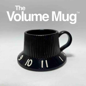 Può includere: Tazza in ceramica nera a forma di manopola del volume, con scanalature verticali e un manico curvo. I numeri 9, 10 e 11 sono visibili sulla base. Il testo "The Volume Mug" è stampato sopra la tazza.