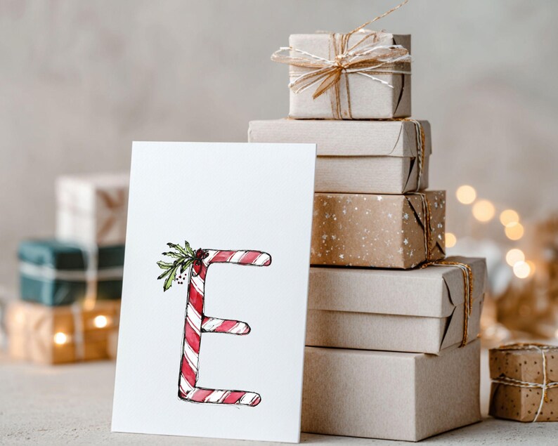 May include: A festive Christmas card with the letter 'E' styled as a candy cane, with red and white stripes and sprigs of holly. A stack of wrapped gifts in brown paper, tied with twine, is in the background, evoking a holiday atmosphere.
