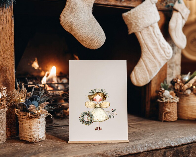 May include: A framed illustration of a fairy with a floral crown and wings, holding a wreath. The fairy is wearing a white dress with gold accents. The artwork is displayed on a wooden stand in front of a fireplace with Christmas stockings.