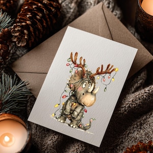 May include: A Christmas card featuring a whimsical illustration of a rhino adorned with antlers and wrapped in colorful Christmas lights. The rhino is wearing a jacket and has a small tail. The card is set against a cozy, textured background with pine cones and a lit candle.