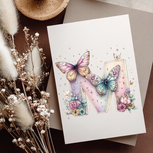 May include: A greeting card featuring a watercolor illustration of the letter "M" decorated with butterflies and flowers. The butterflies have pink, yellow, and blue wings. The flowers are in shades of pink, blue, and yellow.