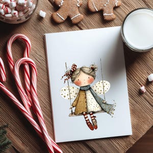 May include: A greeting card featuring a whimsical illustration of a fairy on a swing, with star-shaped wings and a patterned dress. The card is surrounded by candy canes, gingerbread cookies, marshmallows, and a glass of milk, creating a festive holiday scene.