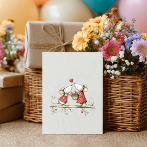 May include: A greeting card featuring two cartoon mice kissing, with a red heart above them. The mice are wearing red and white polka dot outfits. The card is in front of a gift box, flowers, and a basket.