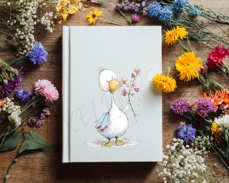 May include: A white journal with a whimsical illustration of a cartoon goose holding a sprig of pink flowers. The goose has a yellow beak and feet, and is wearing a blue scarf. The journal is surrounded by colorful flowers on a wooden surface.