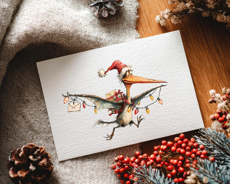 May include: A Christmas card featuring a cartoon pterodactyl wearing a Santa hat and carrying gifts and string lights. The pterodactyl has a long beak and is depicted in flight. The card is on a white background with holiday decorations.