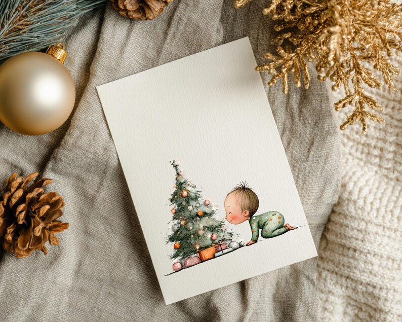 Puede incluir: Una tarjeta navide&ntilde;a de acuarela con un beb&eacute; con un mono verde que se arrastra hacia un &aacute;rbol de Navidad decorado con regalos. La tarjeta est&aacute; sobre una superficie de lino neutro con adornos dorados y pi&ntilde;as.