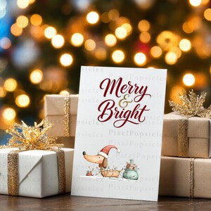 May include: A white greeting card with the red text Merry & Bright, featuring a cartoon dachshund wearing a Santa hat and tangled in Christmas lights, surrounded by gift boxes wrapped in brown paper with gold glitter ribbons.