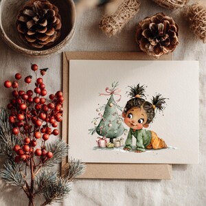 Puede incluir: Tarjeta de felicitaci&oacute;n navide&ntilde;a con una ilustraci&oacute;n en acuarela de una ni&ntilde;a peque&ntilde;a que se arrastra hacia un &aacute;rbol de Navidad decorado. La tarjeta est&aacute; sobre un fondo neutro con pi&ntilde;as y bayas rojas.