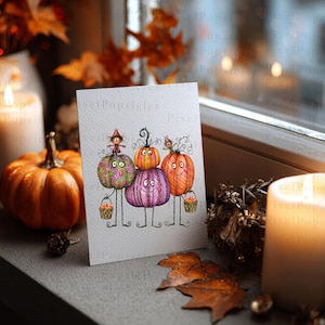 May include: A white greeting card featuring a whimsical illustration of three stacked pumpkins with faces, thin stick-like legs, and arms holding small baskets. The pumpkins are coloured in shades of green, purple, and orange with detailed line work.