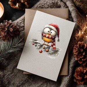 May include: A Christmas greeting card featuring a cartoon bird wearing a Santa hat and a red and white striped scarf, perched on a snow-covered branch with ornaments. The card is on a neutral background with a brown envelope.